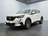 Une voiture blanche est garée dans une grande pièce au sol noir.