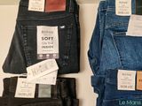 three pairs of men ' s jeans sitting on top of a white table