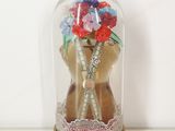 a glass dome with a teddy bear holding a bouquet of flowers