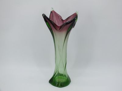 un vase en verre violet et vert posé sur une surface blanche