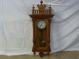 une horloge posée par terre devant un fond blanc