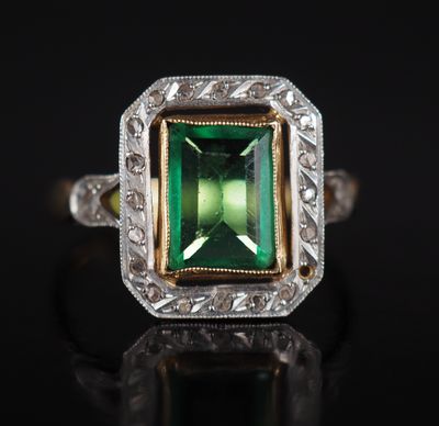 un gros plan d'une bague en tourmaline verte posée sur une surface noire