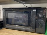 a black microwave sitting on a shelf in a kitchen