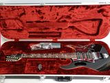 a black electric guitar in a case on a white surface