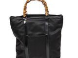 un sac fourre-tout noir avec des anses en bambou sur fond blanc