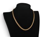 a gold chain necklace on a black mannequin