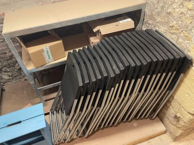 une pile de chaises posée sur une palette à côté d'une pile de cartons