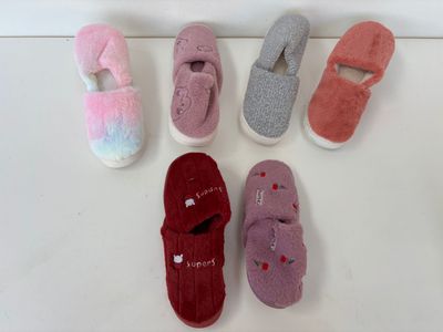 Plusieurs paires de chaussons sont alignées sur une surface blanche