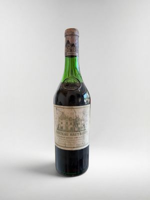 une vieille bouteille de vin posée sur une surface blanche