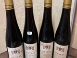 four bottles of wine are lined up on a wooden table