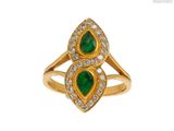un gros plan d'une bague en or sertie de pierres vertes et de diamants