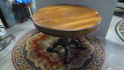 une petite table ronde avec un plateau en bois, posée sur un tapis