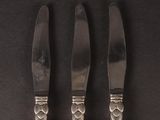three silverware pieces on a black surface with a knife and fork