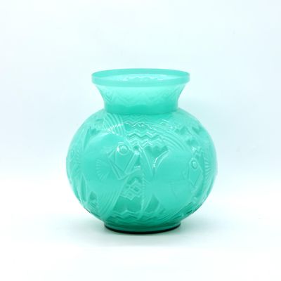 un vase vert posé sur une surface blanche