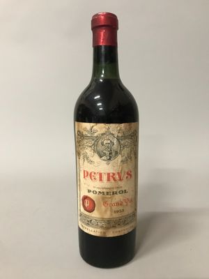 une vieille bouteille de vin rouge posée sur une table blanche