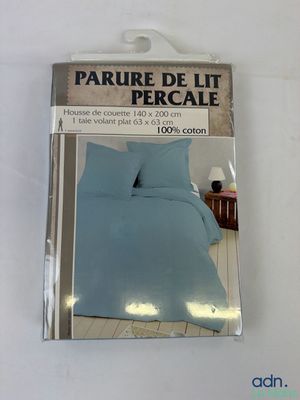 emballage d'un lit avec une couette bleue et un oreiller blanc