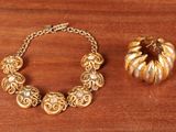 a gold bracelet and a gold pumpkin on a wooden table
