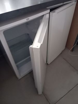 un petit réfrigérateur dont la porte est ouverte et repose sur le sol