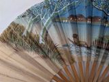a fan with a painting of a boat on the water