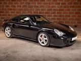 a picture of a black sports car parked in front of a brick wall