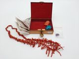 une boîte rouge contenant un tas de perles rouges et une perle rouge
