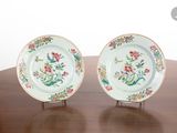 two plates with floral designs on them sitting on a wooden table