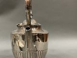an image of a silver vase with a handle on a table