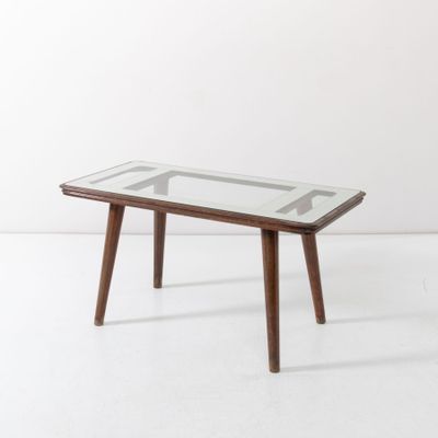une photo d'une table basse avec un plateau en verre et des pieds en bois
