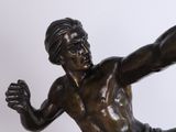 bronze statue of a man kicking a soccer ball on a white background