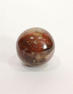 une boule de marbre posée sur une surface blanche, avec un fond blanc
