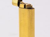briquet en métal jaune posé sur une surface blanche, avec un fond blanc