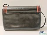 the small black purse is sitting on a white surface