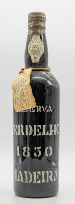 une vieille bouteille noire avec une étiquette, posée sur une surface blanche
