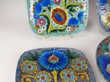 three decorative plates with flowers and birds on them on a white surface