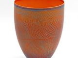 un vase orange et bleu posé sur une surface blanche