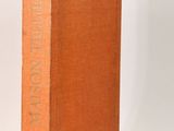 an orange book sitting on top of a table next to a white wall