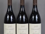 three bottles of wine are lined up on a glass table