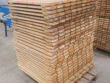 plusieurs piles de bois empilées sur des palettes dans un entrepôt
