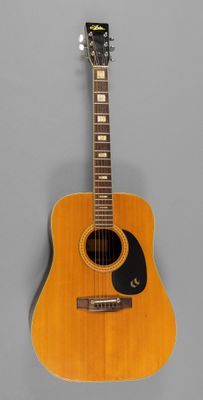 un gros plan d'une guitare acoustique sur fond gris