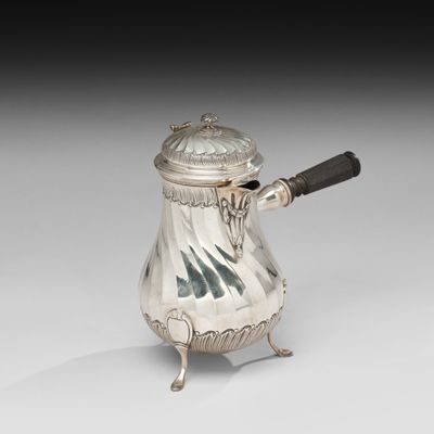 une cafetière ancienne en argent, munie d'une anse et posée sur un socle