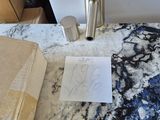 une table en marbre sur laquelle est posé un mot, à côté d'une boîte de papier toilette