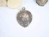 a silver pendant that has a picture of a woman on it