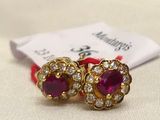 pair of ruby and diamond earrings on a white cloth with a red ribbon