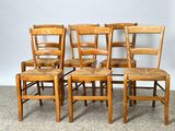 four wooden chairs are lined up in a row on a carpeted floor