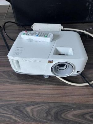 a white projector sitting on a wooden floor next to a black bag