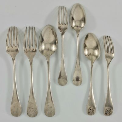 six fourchettes et cuillères sont disposées en ligne sur une surface blanche