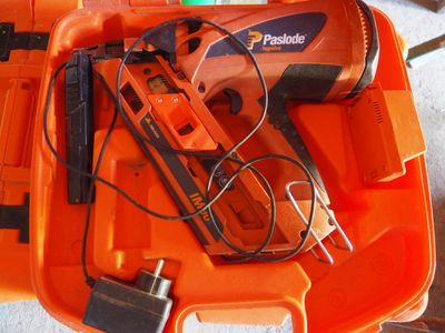 une boîte à outils orange posée par terre, contenant des outils