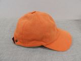 a close up of an orange baseball cap on a gray surface