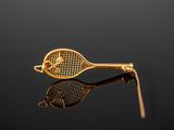 a gold tennis racket and a ball on a black surface