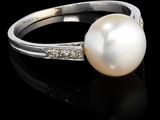 une bague en perles blanches et diamants sur une surface noire